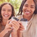 Coffee, selfie and couple of friends outdoor, park or city for social media post, profile picture and gen z lifestyle. Happy diversity people, influencer or youth with cafe drink and smile portrait.